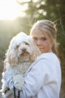 Girl holding dog and looking at camera, differential focus — Stock Photo