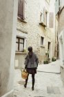 Вид сзади на молодую женщину, идущую по старому городу — стоковое фото