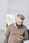 Mann mit Kopfhörer beim Hören auf Smartphone, selektiver Fokus — Stockfoto