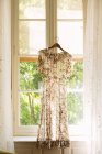 Kleid mit Blumenmuster hängt im Fenster — Stockfoto