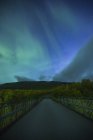 Сельская дорога ночью с северным сиянием в Швеции — стоковое фото