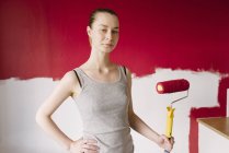 Ritratto di donna con rullo di vernice contro muro — Foto stock