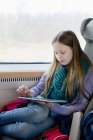 Девушка в поезде играет на цифровом планшете, избирательный фокус — стоковое фото
