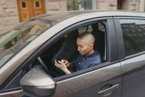 Giovane utilizzando smart phone in auto, messa a fuoco differenziale — Foto stock