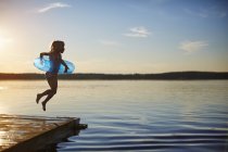 Side view of girl jumping off pier — Stock Photo