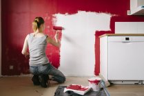 Вид ззаду жінки, що малює стіну на кухні — стокове фото
