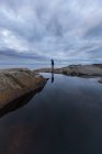 Donna in piedi vicino alla piscina rocciosa sotto cielo coperto — Foto stock