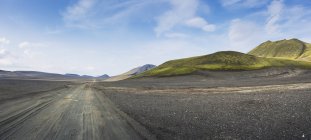 Camino de tierra bajo el cielo azul, Islandia - foto de stock