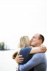 Sorridente coppia abbracciare con lago in background — Foto stock