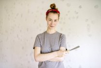 Portrait of young woman holding hand tool — Stock Photo