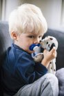 Мальчик с светлыми волосами, пустышкой и игрушкой — стоковое фото