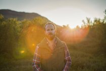 Man in countryside with lens flare, focus on foreground — Stock Photo