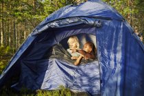 Filles dans la tente bleue à la forêt, se concentrer sur l'avant-plan — Photo de stock