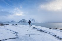 Чоловік стоїть в снігу з видом на море — стокове фото