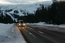 Voiture sur la route par les arbres en hiver, Suède — Photo de stock