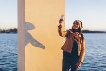 Mulher tomando selfie por mar, foco em primeiro plano — Fotografia de Stock