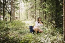 Молодая женщина фотографируется с камерой в лесу — стоковое фото
