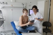 Teenager und Krankenschwester schauen auf digitales Tablet, Fokus auf Vordergrund — Stockfoto