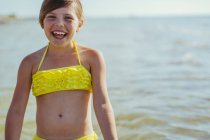 Menina sorridente ao lado do mar, foco em primeiro plano — Fotografia de Stock