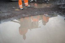 Miners reflecting in puddle, selective focus — Stock Photo