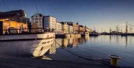 Harbor houses reflecting in water and moored yacht in sunlight — Stock Photo