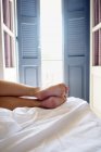 Cropped view of person lying on bed at room — Stock Photo