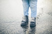 Criança vista cortada em pé no asfalto, foco seletivo — Fotografia de Stock