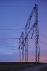 Vista panorâmica dos fios elétricos no campo ao pôr do sol — Fotografia de Stock