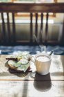 Крупным планом кофе в белой чашке и сэндвич с сыром и огурцами — стоковое фото