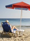 Mujer tomando el sol y leyendo libro en la playa - foto de stock