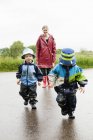 Mutter und Kinder laufen auf nasser Straße — Stockfoto