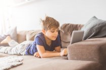 Junge auf Sofa spielt mit Tablet-PC — Stockfoto