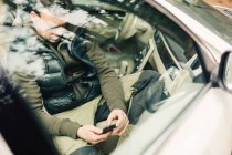 Man using smart phone behind car — Stock Photo