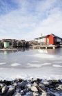 Casa de madera roja por mar congelado - foto de stock