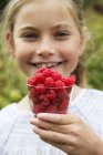 Girl with cup of raspberries, focus on foreground — Stock Photo
