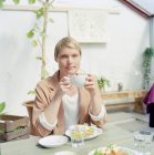 Mitte erwachsene Frau mit Tasse Kaffee, Fokus auf den Vordergrund — Stockfoto