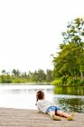 Ragazza sdraiata sul molo accanto al lago — Foto stock