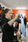 Young woman waxing hockey stick in locker room — Stock Photo