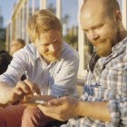 Двоє чоловіків використовують мобільний телефон, диференційований фокус — стокове фото