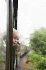 Мальчик, выглядывающий в окно — стоковое фото
