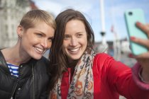 Dos mujeres tomando selfie en el teléfono inteligente, se centran en primer plano - foto de stock