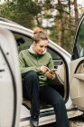 Young woman sitting in car on smart phone — Stock Photo