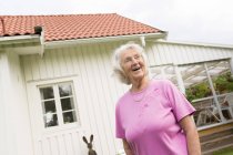 Donna anziana che ride e distoglie lo sguardo nel cortile — Foto stock