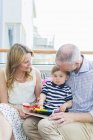 Grandfather and grandmother sitting with baby boy on balcony — Stock Photo