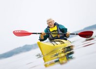 Старший чоловік веслує на байдарці, вибірковий фокус — стокове фото