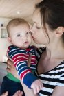 Femme portant et embrassant bébé garçon — Photo de stock
