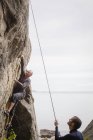 Zwei Männer erklimmen Klippe, konzentrieren sich auf den Vordergrund — Stockfoto