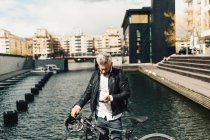 Un homme sur un téléphone intelligent avec une bicyclette à Stockholm, Suède — Photo de stock