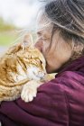 Mujer llevando y besando gato, enfoque selectivo - foto de stock