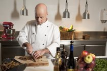Chef guardando giù e tagliando il cibo in cucina — Foto stock